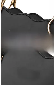 Detail of wave-cut edge and gold hardware on black leather handbag with gold logo