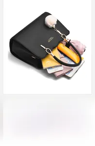 Top view of spacious black leather handbag showing items like a phone and umbrella inside