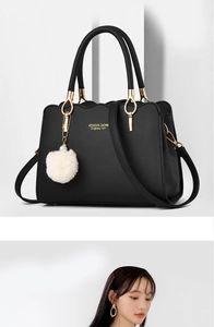 Detail of black faux leather tote with scalloped edge, gold hardware and plush charm