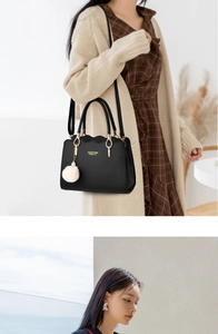 Detail of black wave-edge handbag with gold hardware and a white plush ball charm