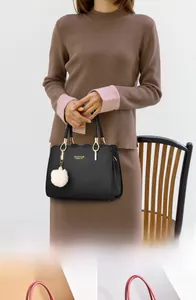 Detail of elegant black tote bag with white plush ball charm and wave-edge pocket design