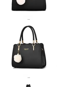 Detail of black leather handbag with scalloped edges, gold hardware, and pearl fur charm