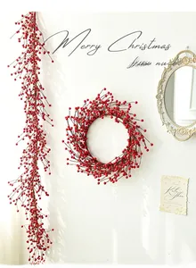 Close-up of artificial red berry wreath and long garland hung for Christmas wall decoration