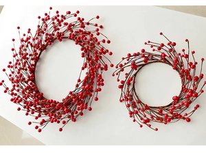 Close-up of two red berry Christmas wreaths in different sizes on white background