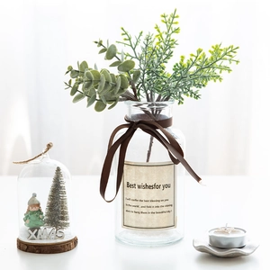 Green artificial pine needle and eucalyptus arrangement in a clear glass vase for Christmas
