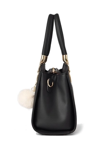 Minimalist black leather tote bag with gold hardware and white pom-pom charm side view