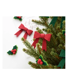 Close-up of red and green felt bow and holly leaf decorations on a Christmas tree branch