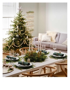 Detailed Christmas table setting with golden candle holder and evergreen wreath centerpiece
