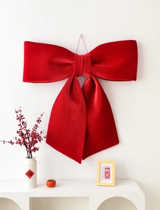 Detail view of large red velvet Christmas bow hanging with festive home decor accents
