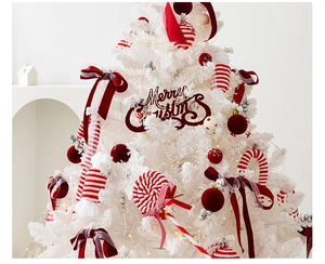 Detail of white Christmas tree with red velvet bows and candy cane ornaments