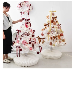 White artificial Christmas tree set with red ornaments and paper base on display