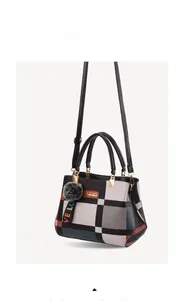 Detail of color-block plaid handbag with gold hardware and plush pompom charm