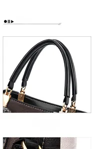 Detail view of denim blue handbag featuring black leather handle and golden metal buckles