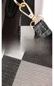 Detail of gold metal fastener and strap on plaid woven tote bag with textured fabric