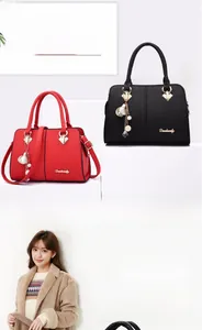 Close-up of textured leather handbag with gold accents and elegant pearl charm detail