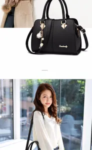 Detail of black pebbled leather tote with gold hardware and floral pearl pendant charm