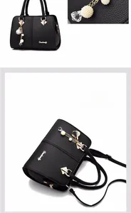 Detail of black pebbled leather tote bag with pearl tassel charm and long shoulder strap