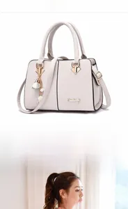 Close-up of beige pebble leather handbag with gold hardware and pearl charm detail