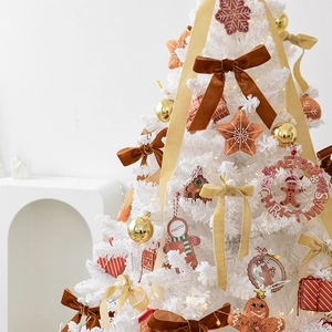 Lush white artificial Christmas tree decorated with gold baubles and velvet bows