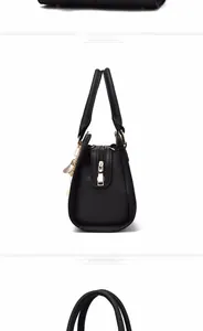 Detail view of black lychee grain leather tote with golden zipper and fringe tassel