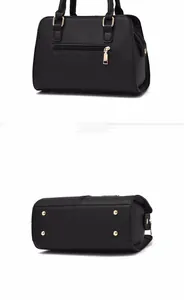 Detail view of the black pebbled leather handbag featuring back zipper and gold metal studs
