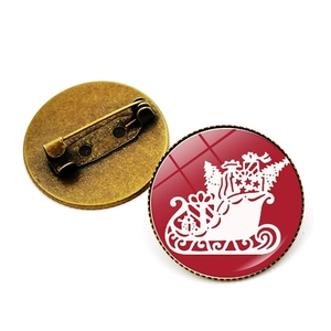Close-up of Christmas brooch showing red sleigh design and bronze safety pin back