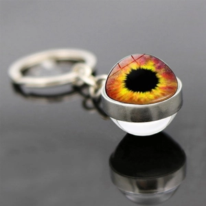 Macro shot of silver evil eye keychain with yellow and red glass marble on reflective surface