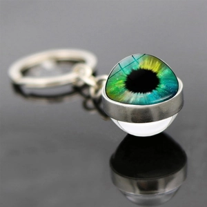 Macro shot of evil eye glass keychain with blue-yellow iris on black reflective surface