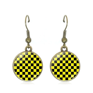 Detail of vintage checkerboard drop earrings with yellow and black patterns and glass dome