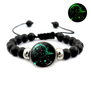 Détail macro du charme lumineux Sagittaire sur un bracelet en perles noires ajustable