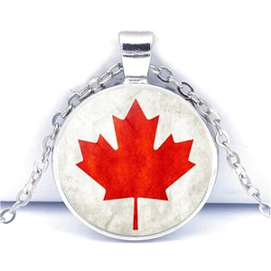 Macro shot of silver round necklace featuring a red maple leaf glass dome pendant