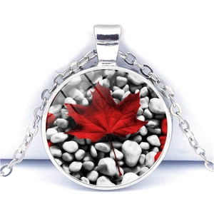 Close-up of Canadian red maple leaf pendant with silver chain on white background