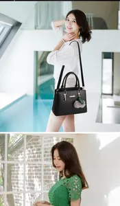 Detail of black pebbled leather handbag with twin handles and decorative grey pompom charm