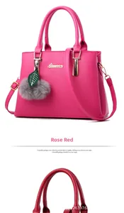 Detail of rose red lychee leather handbag with plush ball pendant and metal logo