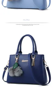 Detail of elegant two-tone faux leather handbag with plush ball charm and logo