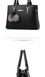 Detail view of black faux leather handbag with gold hardware and plush pompom accessory
