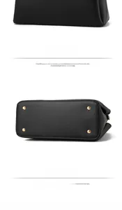 Detail view of the black leather handbag's back and bottom with gold protective metal feet