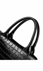 Detalle de la textura de cocodrilo y asa de cuero ergonómica en bolso negro
