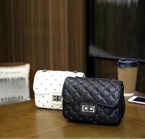Close-up of quilted chain handbags with metal studs and twist-lock on a wooden table