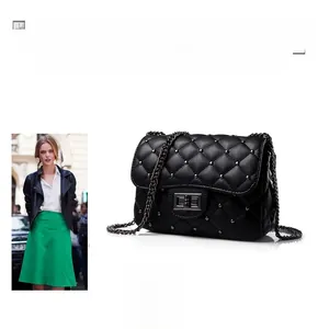 Detail of black quilted shoulder bag featuring metallic studs and a turn-lock closure