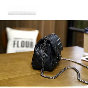 Detail of black quilted crossbody bag with silver studs and chain strap on wooden table