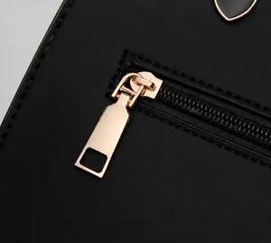 Detalle del tirador de cremallera de corazón dorado y herrajes en bolso de cuero negro