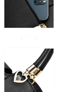 Detailansicht der schwarzen Handtasche aus Litschi-Leder mit Reißverschlussfach und Herzanhänger