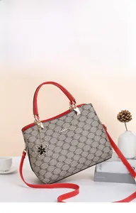 Detail of red handles and gray logo print on women's handbag with floral metal pendant