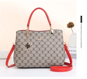 Close-up of beige textured handbag with black MFX prints and red shoulder strap details