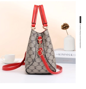 Close-up of monogram canvas handbag with red leather handles and gold-tone hardware