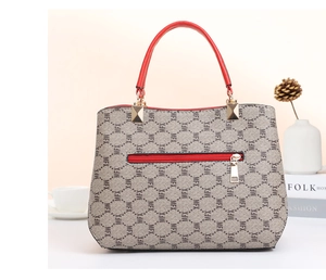 Detail view of monogram pattern ladies handbag with red handles and back zipper pocket