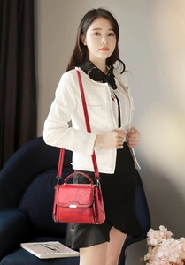 Detail of red faux leather handbag featuring metal plaque and zipper side accents