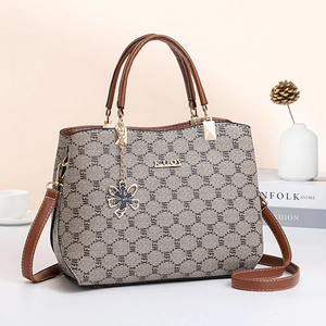 Classic grey printed tote bag with brown leather handles on a minimalist table