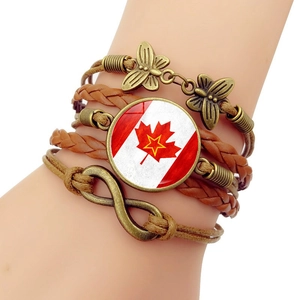 Détail d'un bracelet multicouche en cuir avec papillon en bronze et charme drapeau Canada